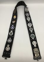 A webbing belt, fitted with numerous vintage chromed, enamelled, and other examples of Police