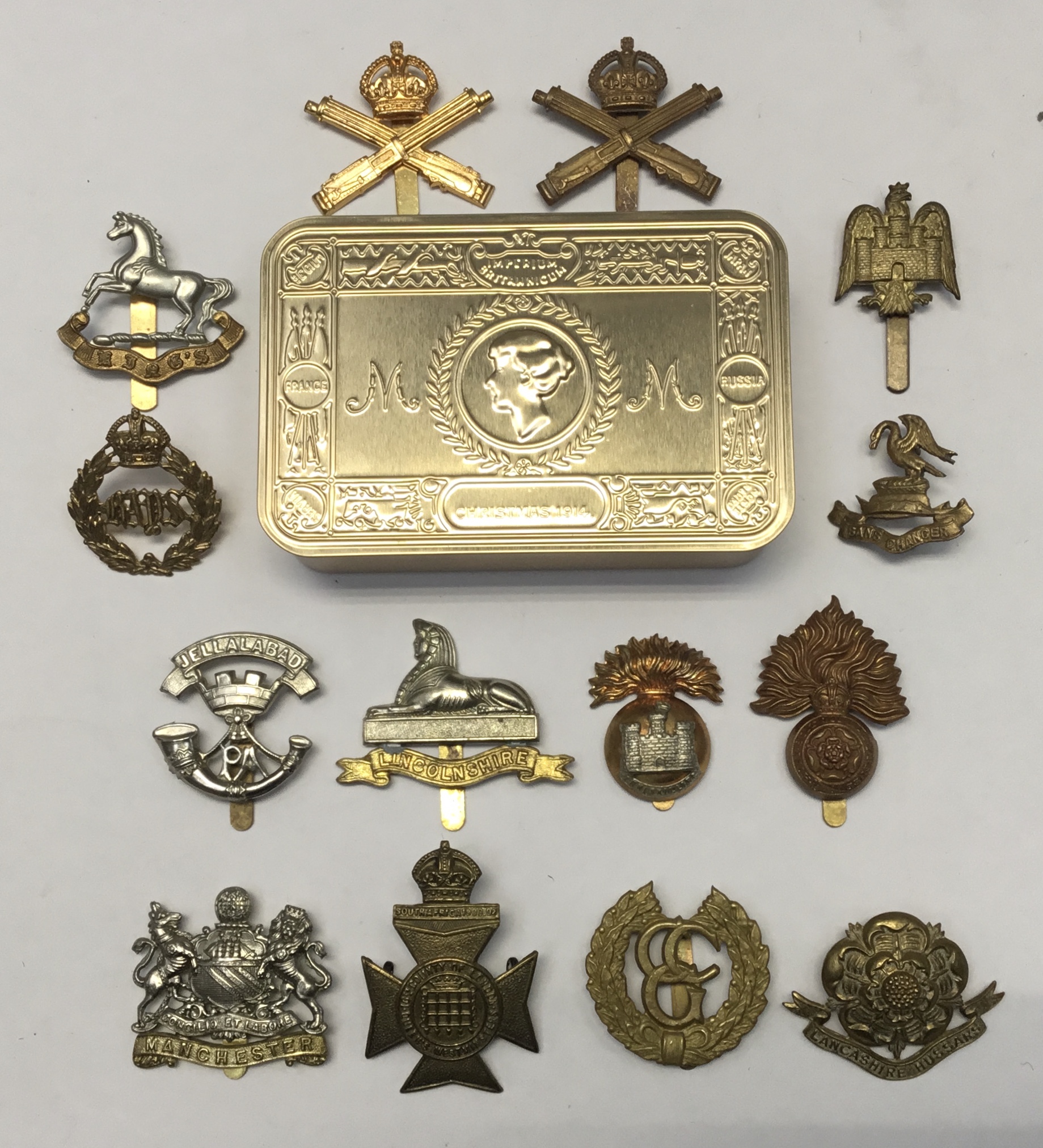 A selection of brass and bi-metal cap badges, plus a WW1 centenary Princess Mary tin (produced in