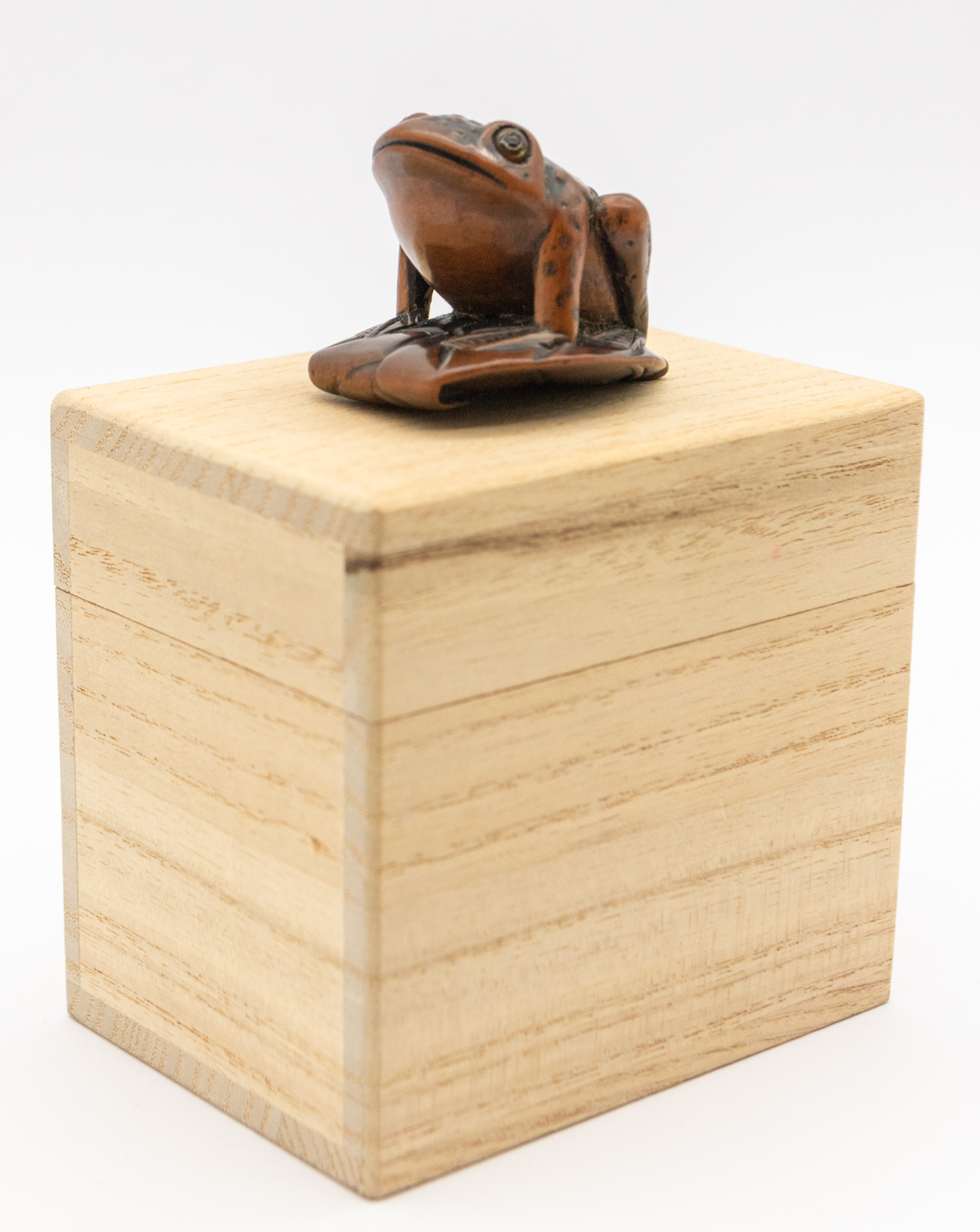 A 19th century Japanese wooden frog netsuke, perching on a leaf with orange eyes, signed underneath, - Image 2 of 5