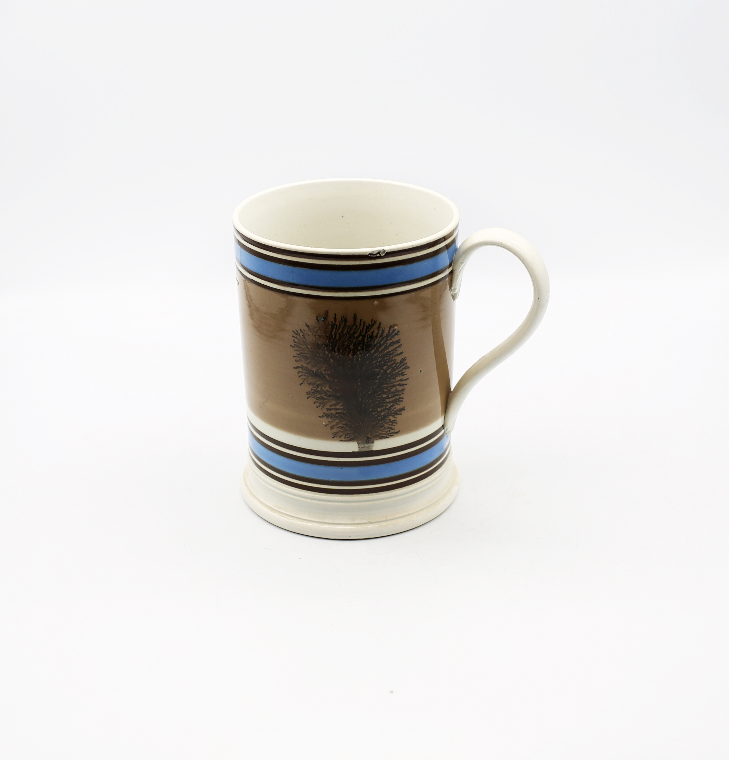 A Mocha ware mug. Quart size, mushroom ground with black feathered trees and blue and black bands
