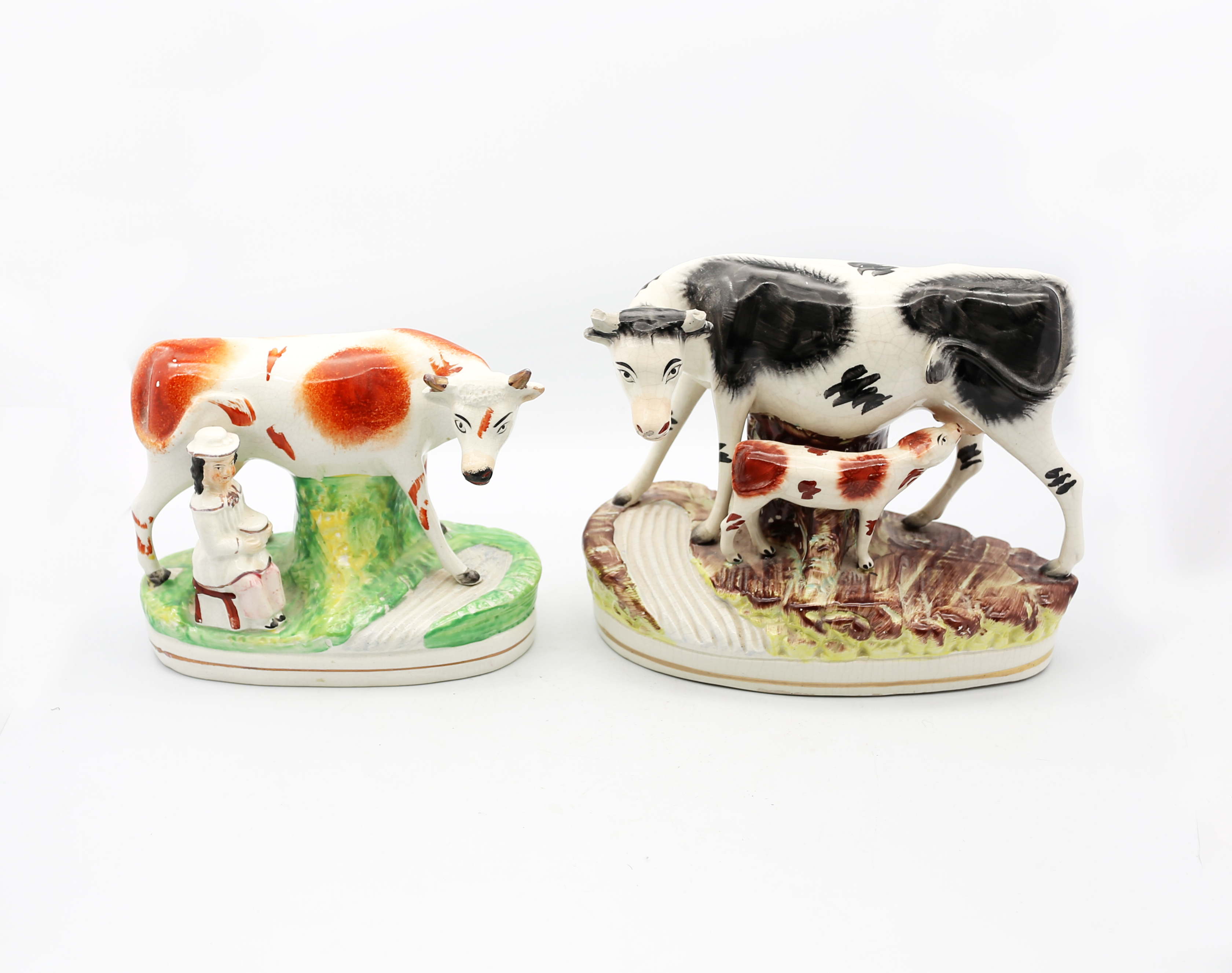 A Victorian Staffordshire pottery Cow and suckling calf standing on a grassy mound by a brook, along
