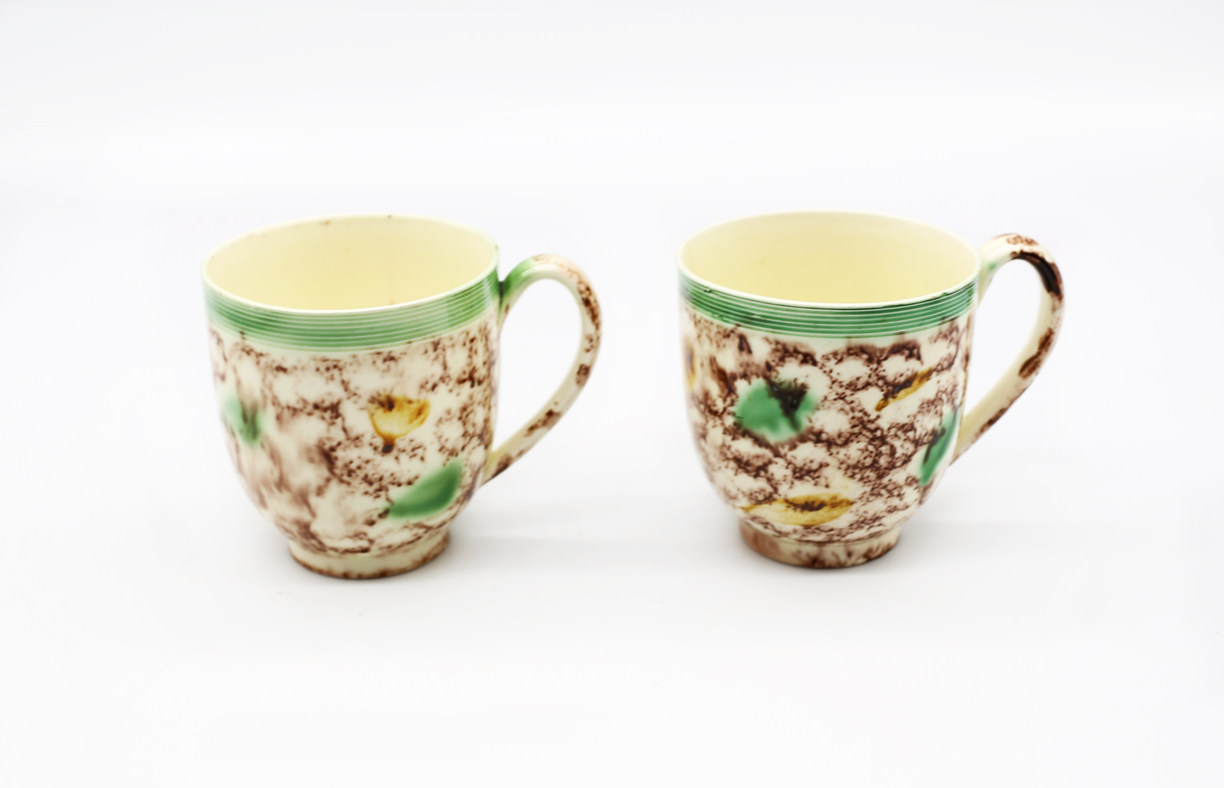 Two Whieldon style creamware coffee cups decorated in copper manganese and yellow.  Circa 1770.