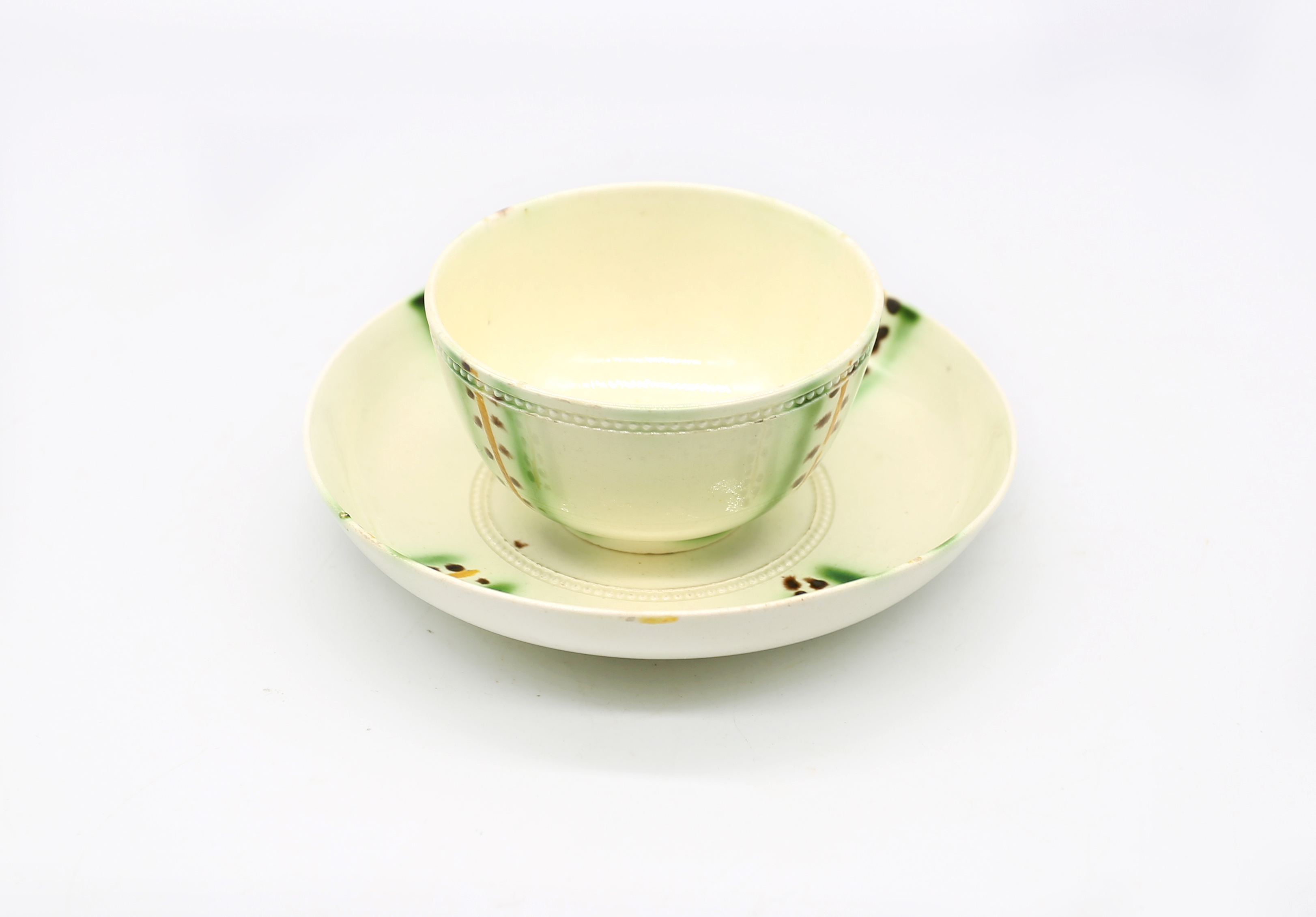 A creamware tea bowl and saucer decorated in copper manganese and yellow.  Circa 1770. Size. TB. 8cm