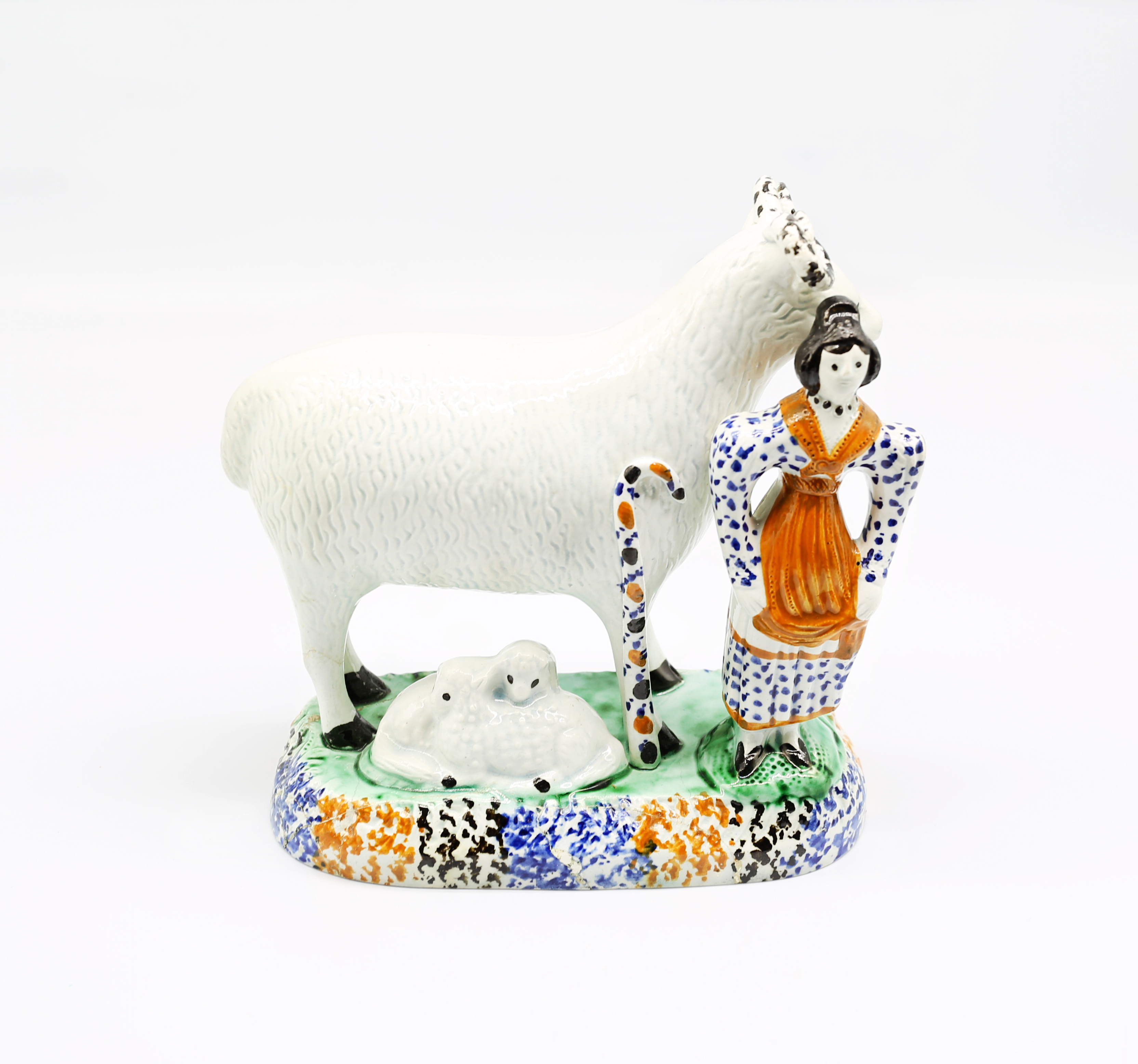 A Prattware model of a sheep and her lambs laying beneath her, with a shepherdess standing to the