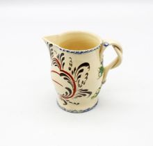 A small Leeds creamware jug with a plough painted in red and black with blue feathered rims and