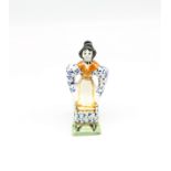 A small Prattware figure of a seated lady, painted in underglaze colours of blue, ochre, black and