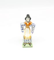 A small Prattware figure of a seated lady, painted in underglaze colours of blue, ochre, black and
