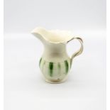 A Leeds creamware jug, with a flared scalloped rim and spout with a crossed strap handle,
