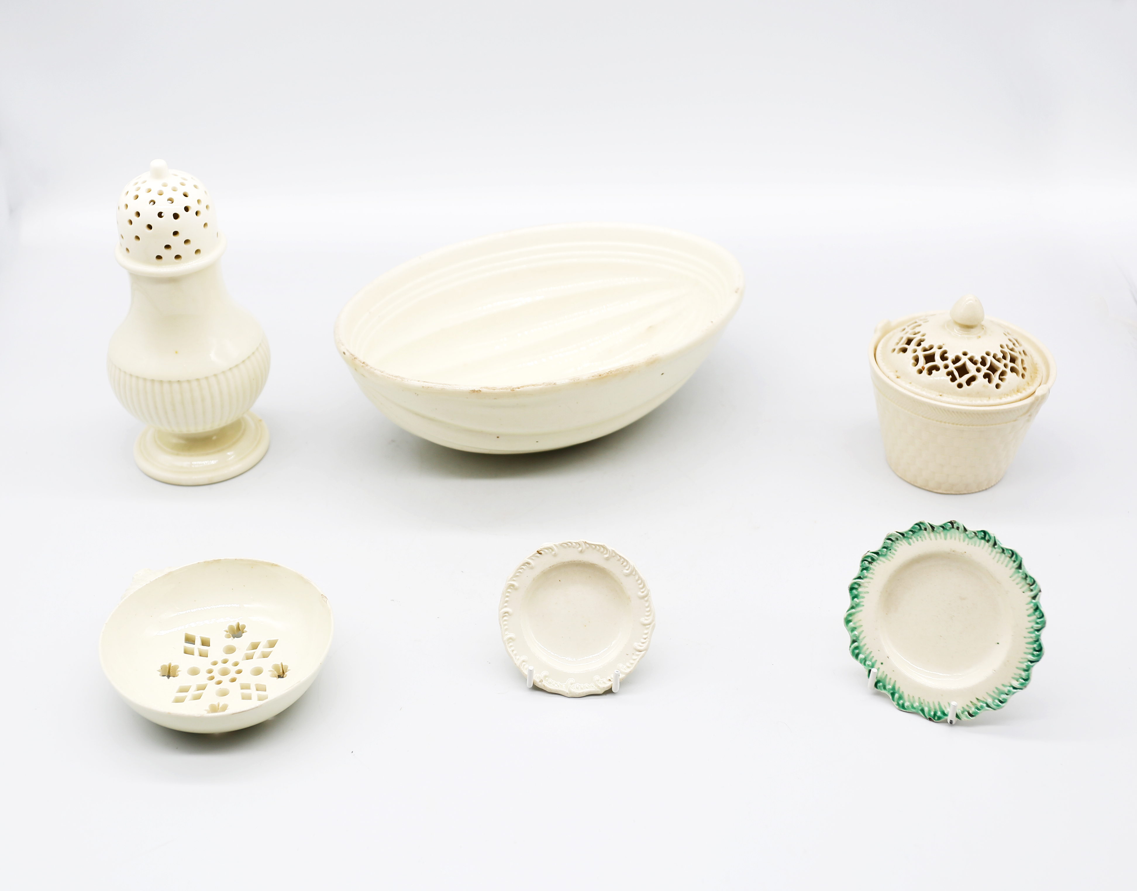 A small collection of creamware to include a melon tureen base, sugar caster, drainer, two miniature