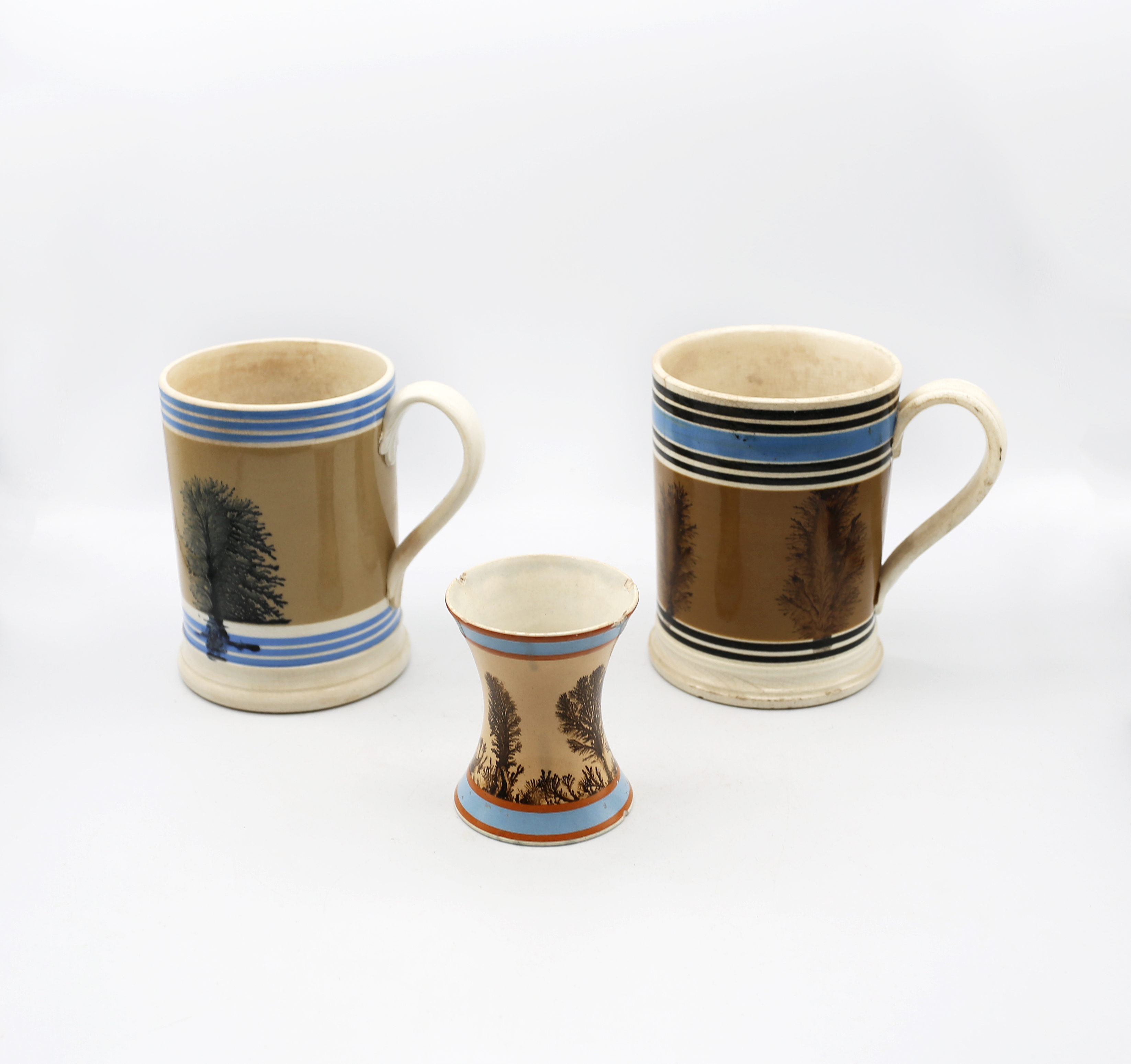 A Mocha ware Quart sized mug, mid brown ground with feathered sepia trees, blue band and six black