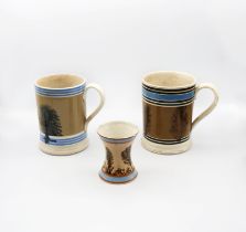 A Mocha ware Quart sized mug, mid brown ground with feathered sepia trees, blue band and six black