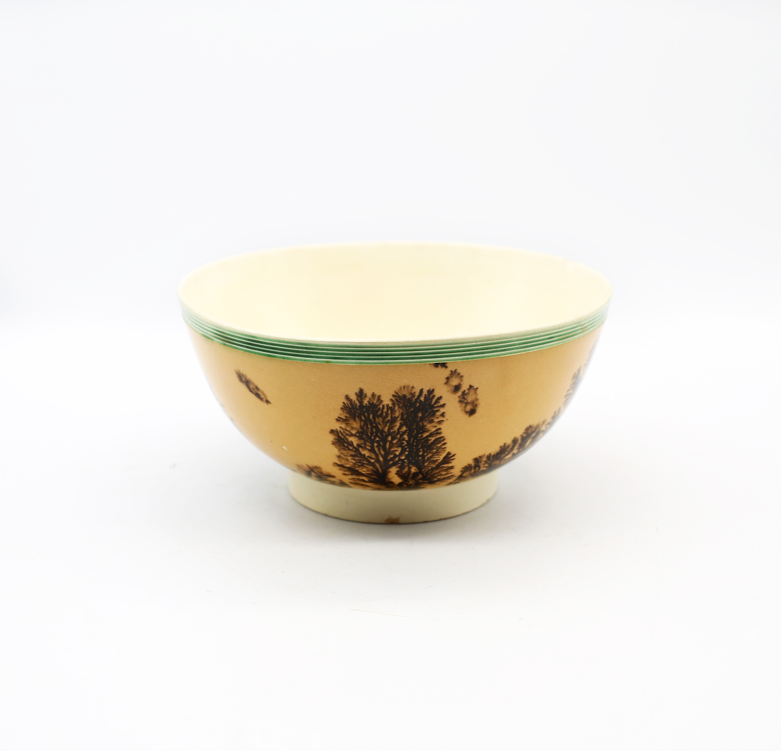 A creamware Mocha bowl, orange ground with black/sepia trees and a green ribbed band to top rim