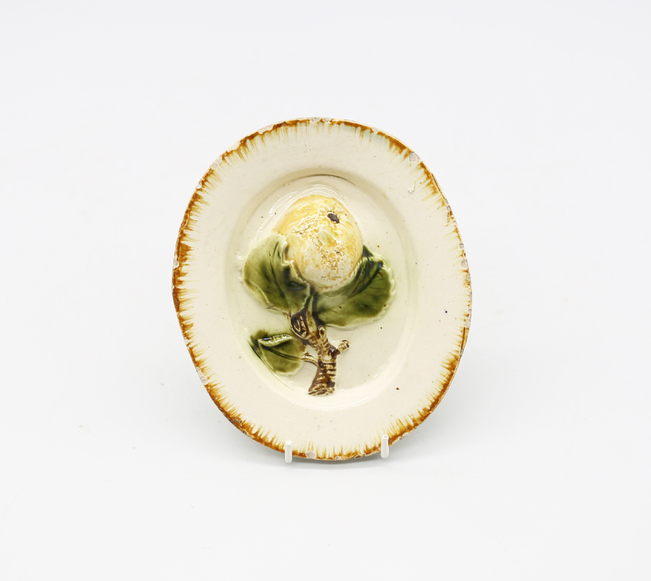 A creamware ‘Toy’ oval platter with an apple and foliage moulded in the centre, with an ochre