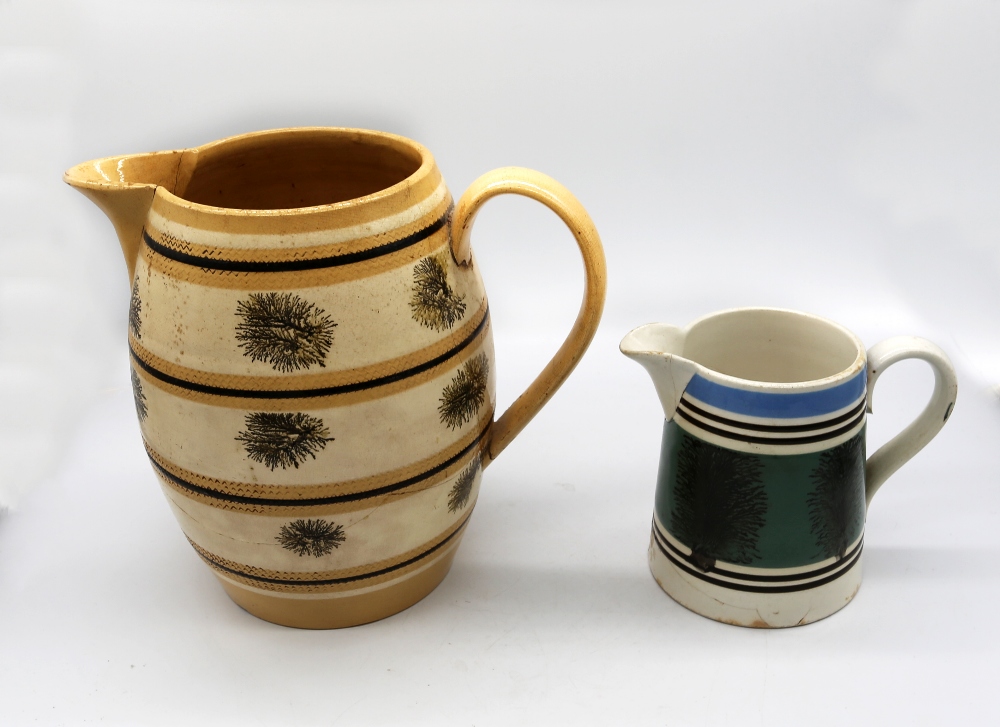 A large mocha ware pitcher, cream ground with ochre and black bands with black trees. C 1810,