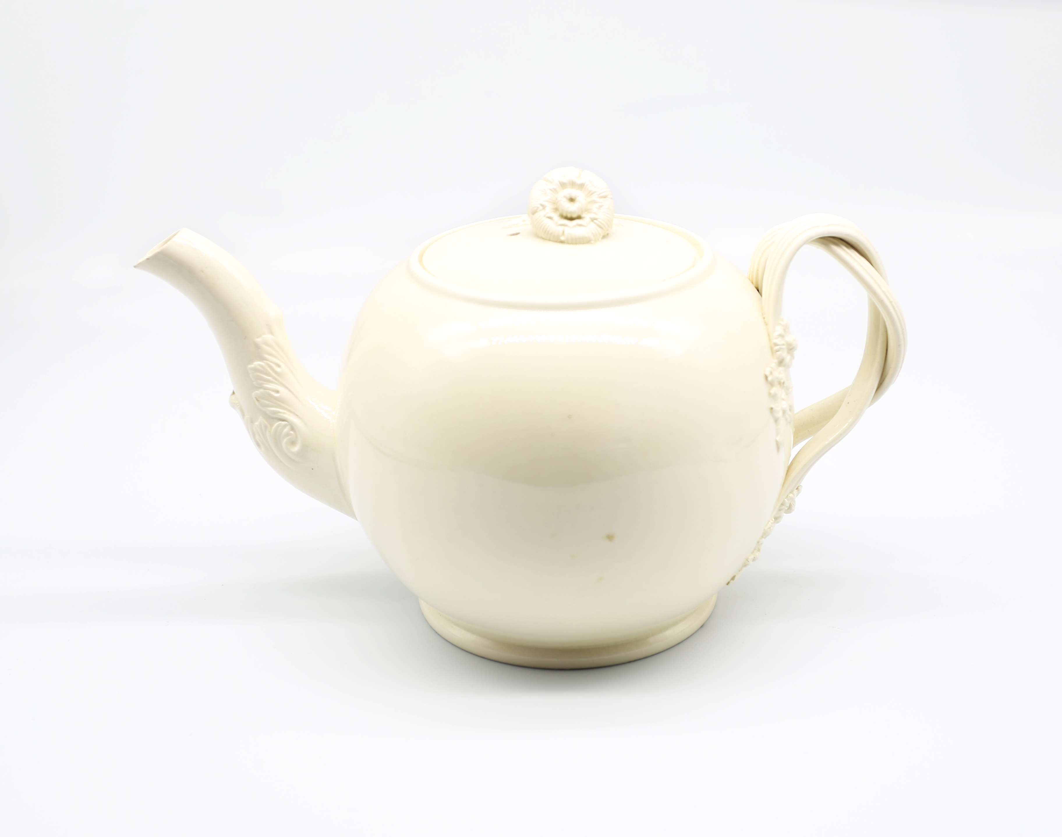 A Leeds creamware globular teapot and cover, with a twisted strap handle and floret terminals, the