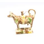 A Staffordshire Whieldon creamware cow creamer standing on an oblong base, sponge decorated in