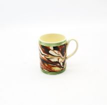 A small creamware cylindrical mug with coloured marbled decoration, with green ribbed bands to top