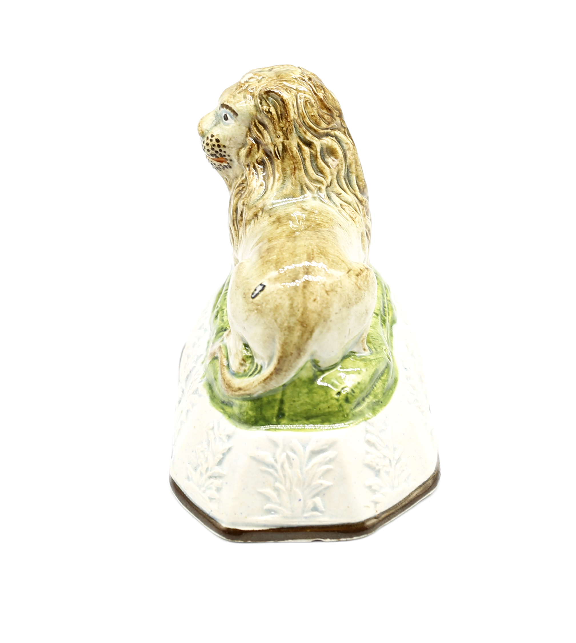 A pearlware model of a recumbent lion laying on a grassy mound on a base with moulded relief.  Circa - Image 2 of 8