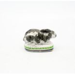 A Staffordshire pottery Rabbit crouched on an oval base, black sponged markings,  with green and