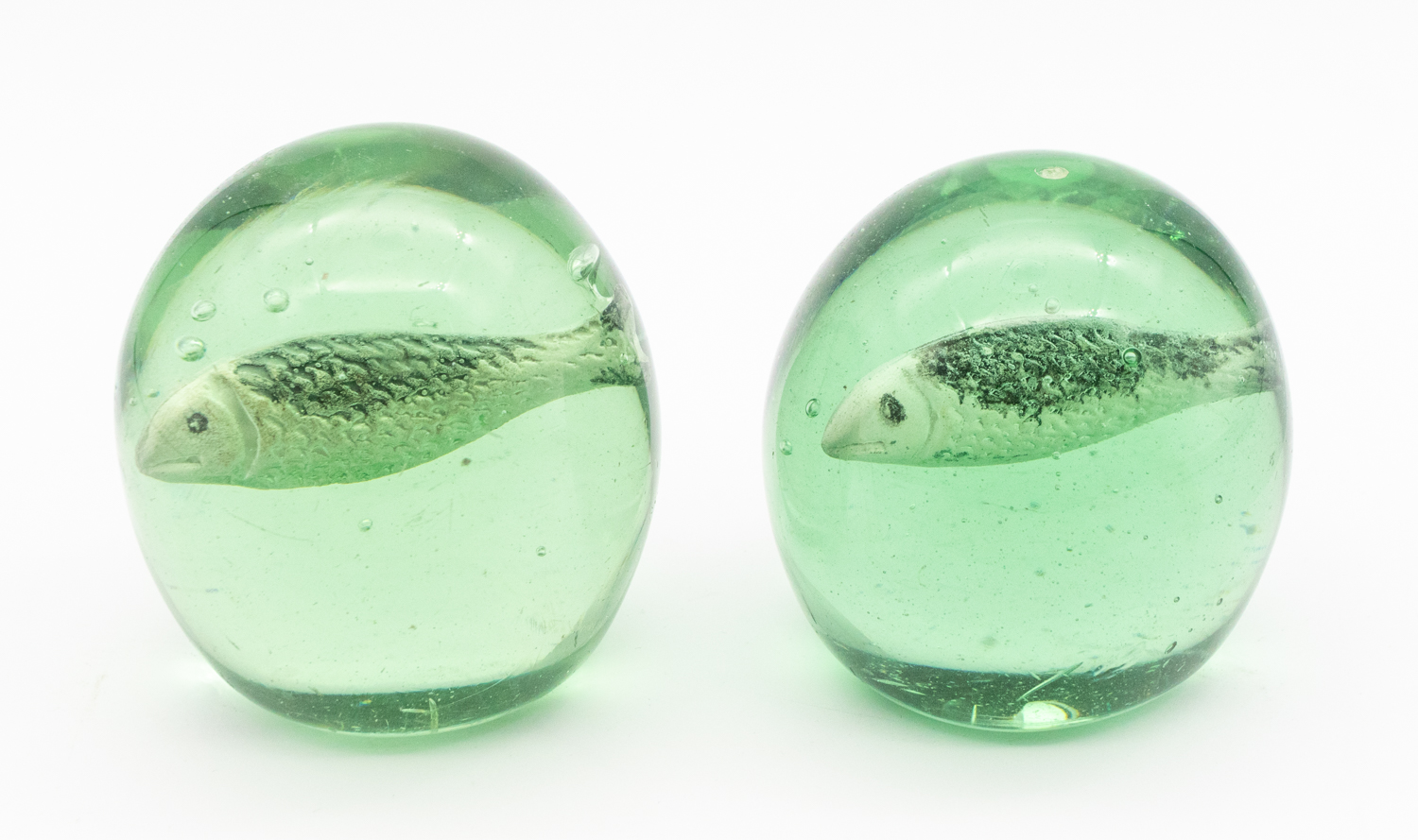 Two Victorian green glass domed paperweights, with sulphide fish designed centres, one slightly