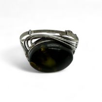 A silver hinged bangle set with green amber