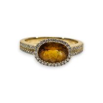 A citrine and diamond set dress ring. Set with a central oval chequerboard cut citrine, measuring