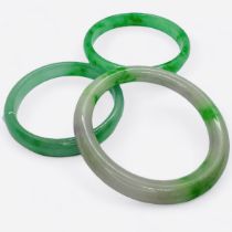 Three jadeite bangles, of graduating sizes.  The first, a "floating flower" green and white jade