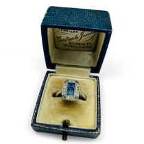 An Art Deco sapphire and diamond set panel ring. Set with two central square cut pale blue