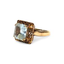 A square cut aquamarine dress ring. Featuring a pale blue aquamarine in a raised openwork setting in