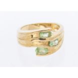 A peridot and 9ct gold cluster ring, comprising a wave like design set with three oval peridots,