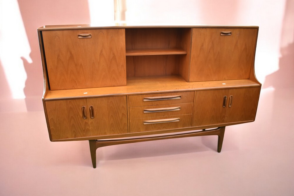 A 1970s G Plan teak sideboard/unit with sliding drawers, cocktail cupboard with base drawers along