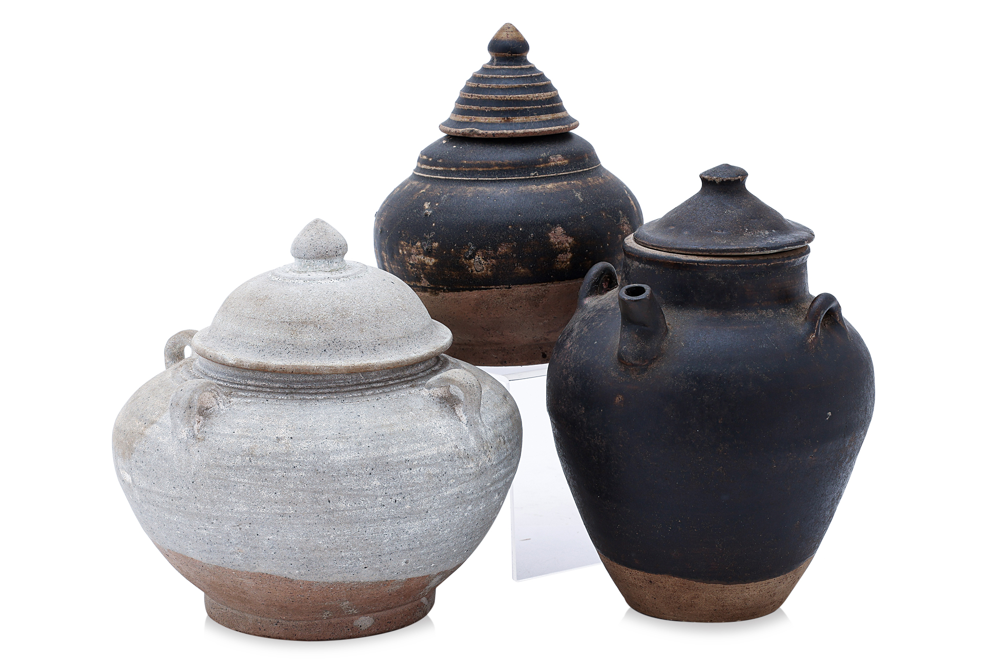 A GROUP OF THREE POTTERY JARS AND COVERS