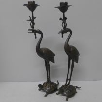 A pair of bronze candlesticks, 20th Century, storks stood on turtles, one beak a/f, 31.5cm