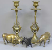A pair of Indian brass candlesticks, two brass oxen and a metal model of a bull