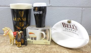 A large pottery Guinness pint glass money bank, one smaller, a Guinness mug and coaster set,