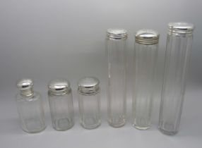 Six silver topped glass bottles, five with monograms to lid