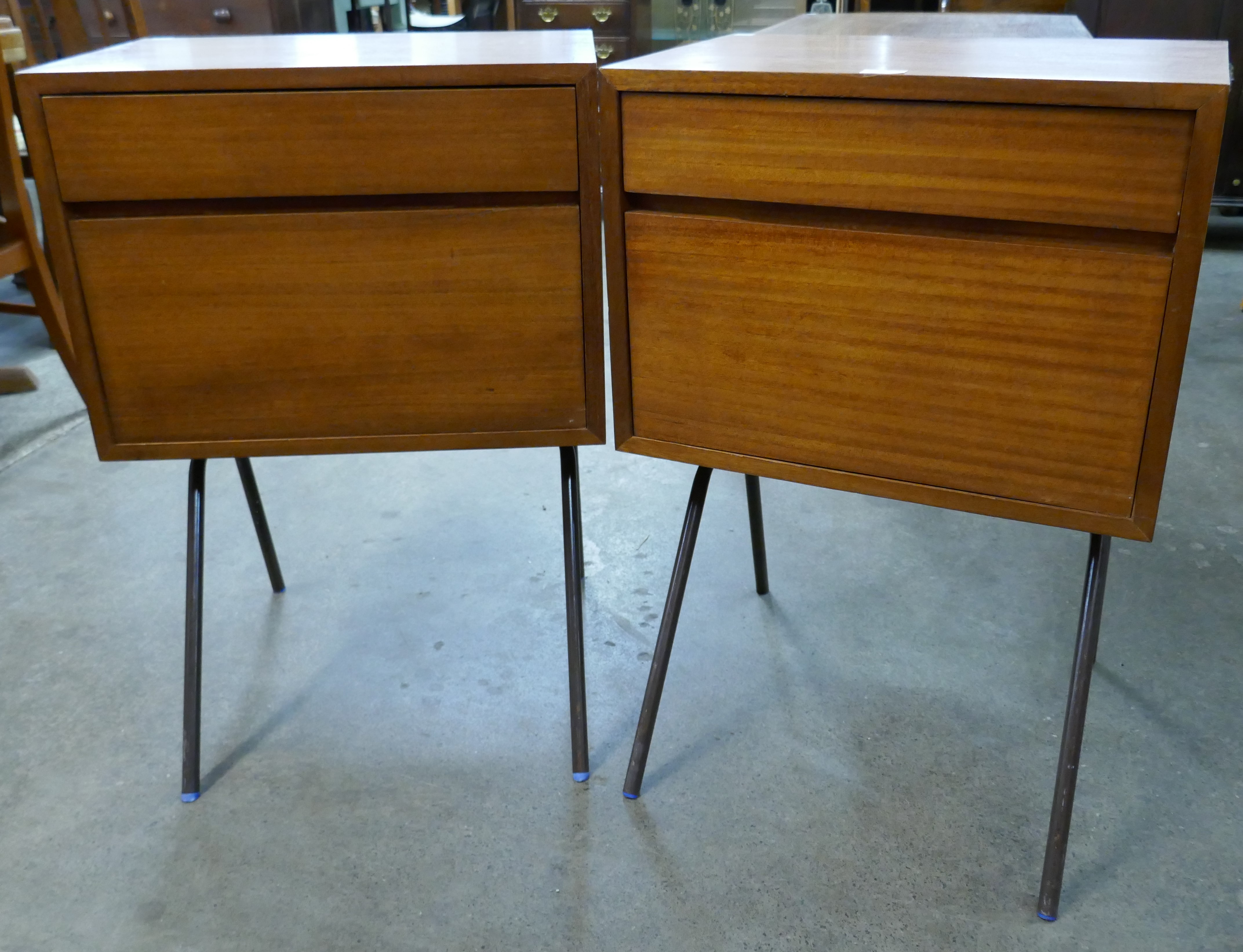 A pair of teak bedside chests on black tubular metal legs