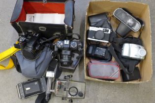 A large black camera box with underwater case and Olympus Trip 35, a black/green case with a Kodak