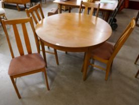 A circular teak extending dining table and four chairs