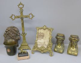 A collection of brassware including a photograph frame, crucifix, Egyptian head brackets, erotic