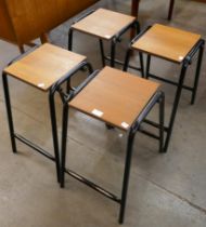 A set of four teak and black tubular metal stools