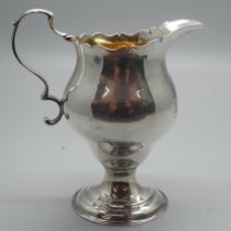 A Georgian silver cream jug with gilt interior, London 1776, with crest, 73g