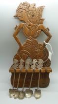 A set of five Eastern .800 silver spoons in a carved wooden display rack