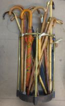 A brass and metal stickstand and a collection of walking sticks and canes