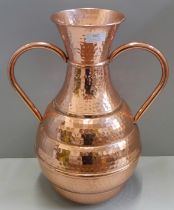 A large hammered copper two handled vase