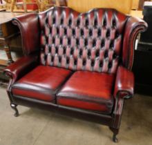 An oxblood red leather Chesterfield wingback settee