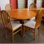 A teak circular extending dining table and four chairs