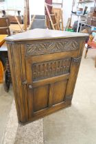 A carved oak corner cupboard