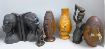 A collection of carved items including a pair of African tribal girl bookends, egg with religious
