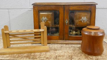 An oak smokers cabinet with bevelled edge glass doors, a tobacco jar, a pipe rack and pipes
